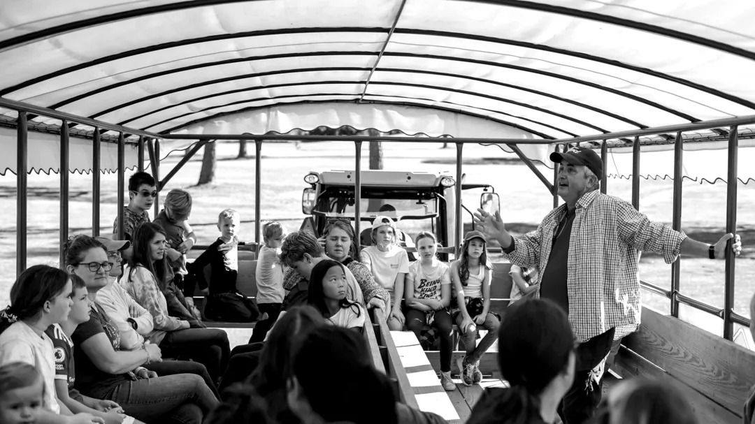 Karson talking to a wagon full of students on the farm's covered wagon ride